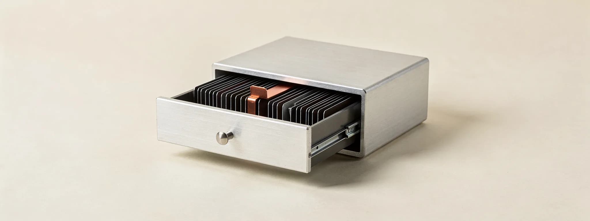 A machined card-index drawer half open, one copper tab standing proud.