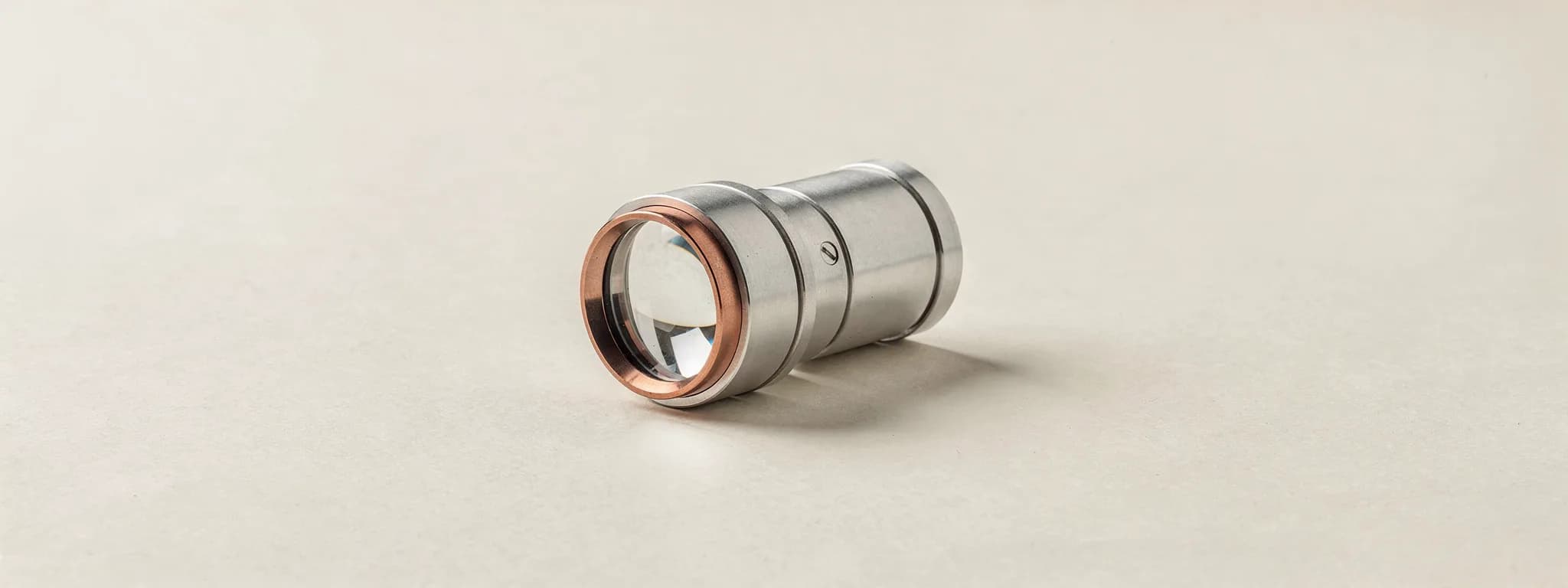 A machined aluminium loupe with a copper ring, lying on its side.