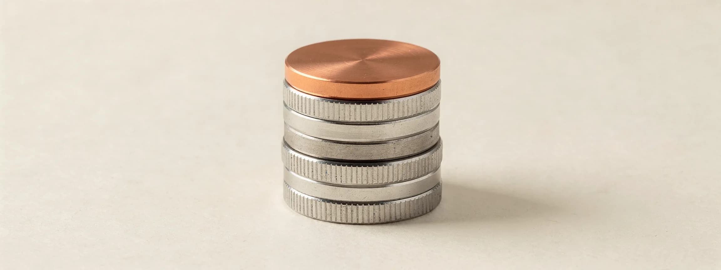 A stack of machined steel coins with one copper coin on top, on paper.