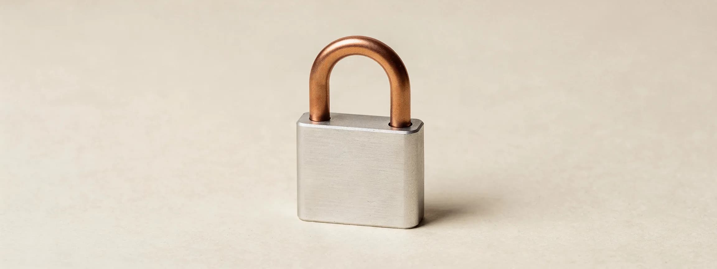 A machined steel padlock with a copper shackle, on paper.
