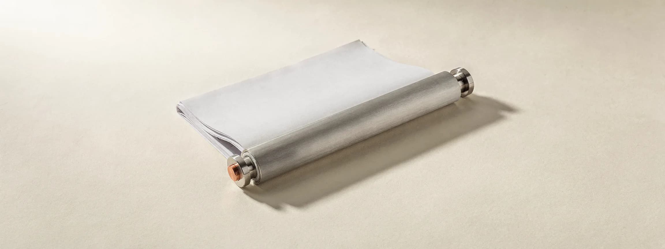 A brushed steel newspaper rod holding one folded sheet, on paper.