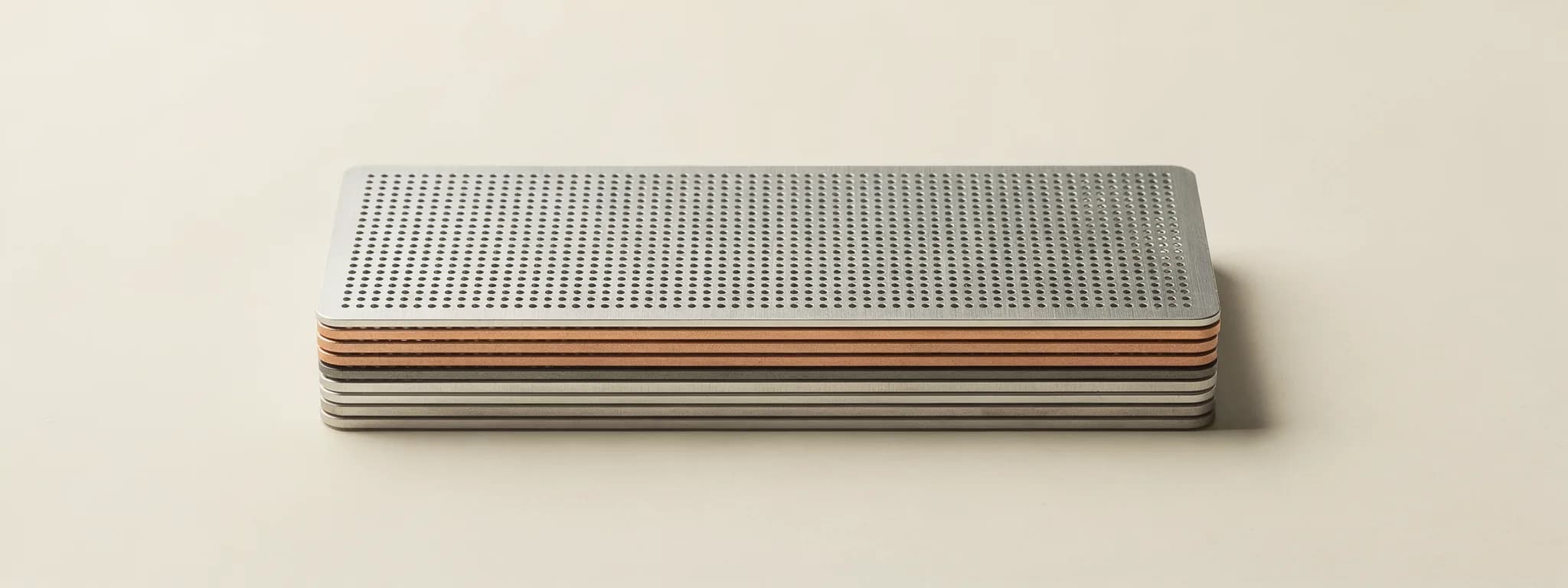 A stack of perforated steel and copper plates on paper.