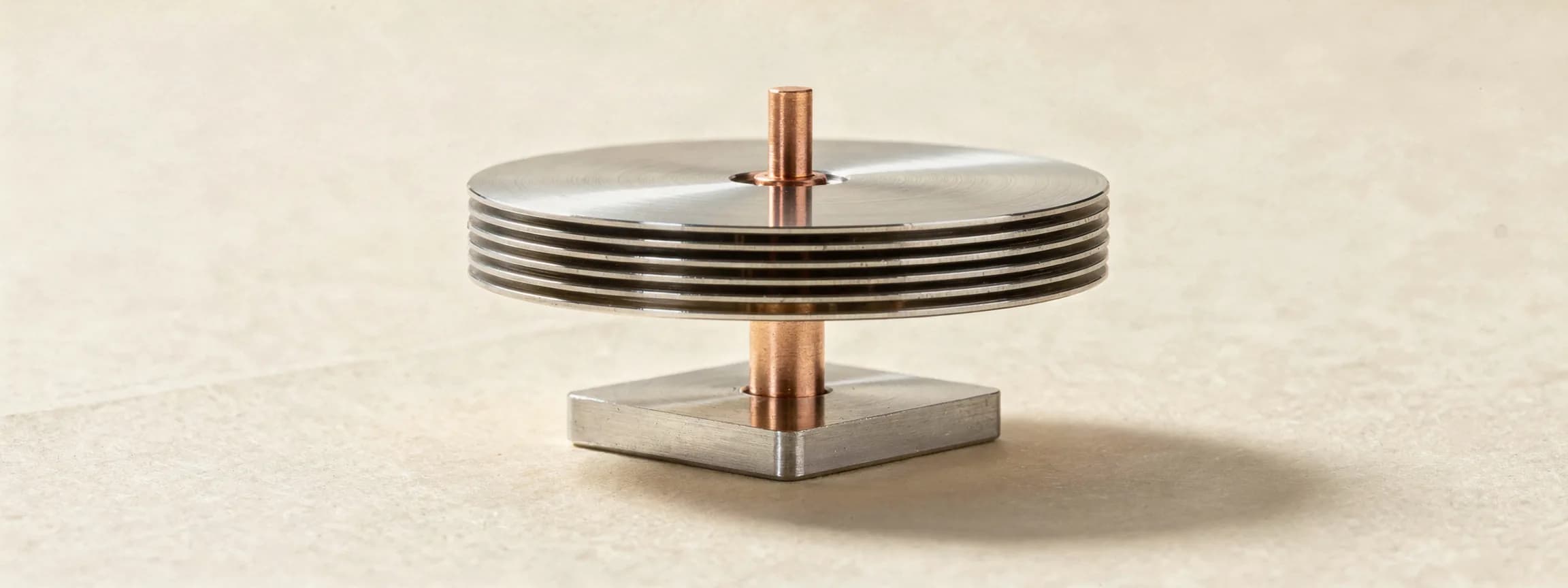 A stack of polished steel drive platters on a copper spindle, on paper.