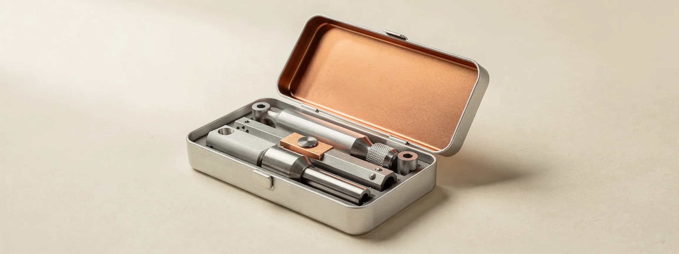 A set of machined steel instruments in a copper-lined case, on paper.