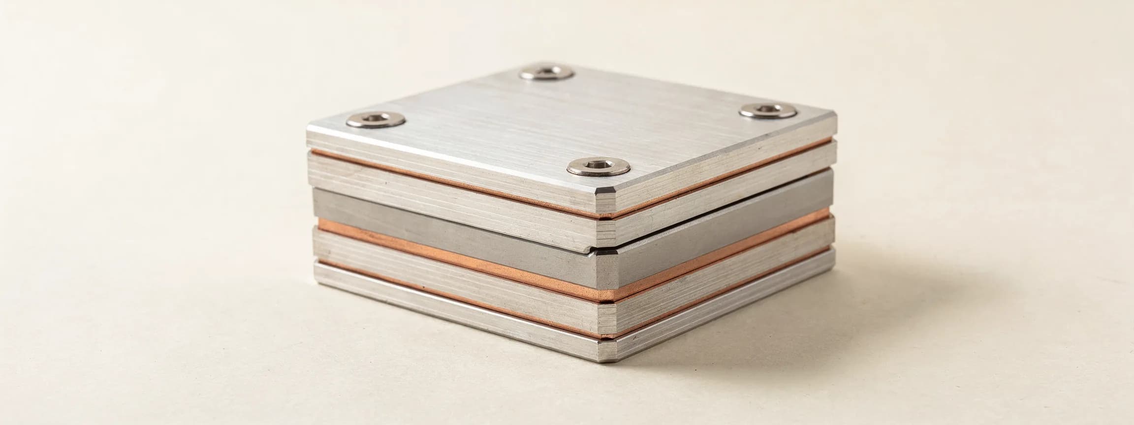 A stack of machined aluminium plates separated by copper spacers, bolted through, on paper.